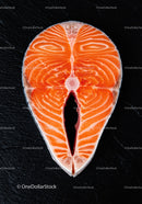 Fresh salmon steak slice on black textured surface