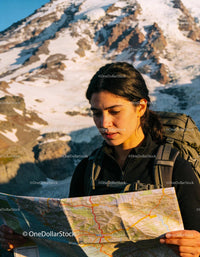 Focused Female Hiker Navigating Mountain Terrain with Map