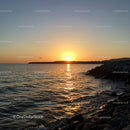 Scenic Sunset Over Rocky Coastline with Calm Ocean Waters