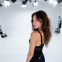 Confident Woman with Wavy Hair and Black Tank Top in Studio Setting