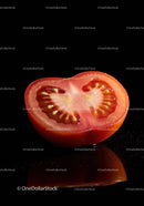 Fresh ripe tomato half on black reflective surface