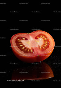 Fresh ripe tomato half on black reflective surface