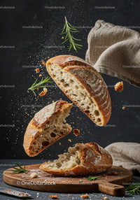 Rustic bread torn apart with fresh rosemary herb on wooden board