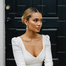 Elegant woman in white dress posing by black door