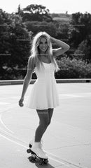 Smiling woman roller skating outdoors in summer dress
