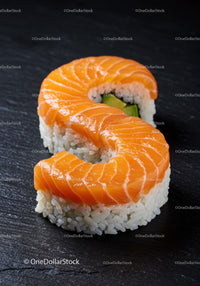 Salmon Sushi Roll Shaped Like Letter S on Black Plate