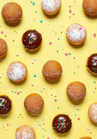 Assorted doughnuts with sprinkles on yellow background