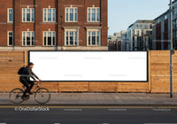 Cyclist passing a blank billboard on urban street