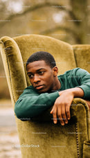 Thoughtful young man resting on vintage armchair outdoors