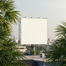 Large blank billboard on rooftop with urban greenery
