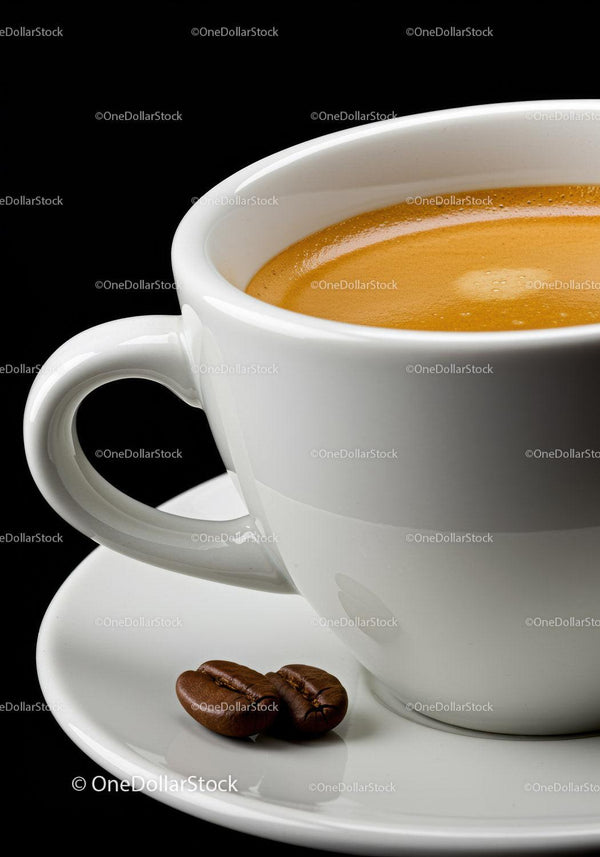 Close-up of fresh espresso in white cup with coffee beans