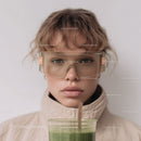 Young Girl with Red Curly Hair Wearing Safety Glasses and Drinking Green Smoothie