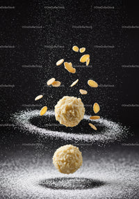 Almond treats with powdered sugar against dark background