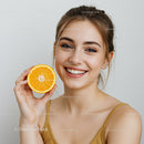 Young Woman Smiling Holding Orange Half Over White Background