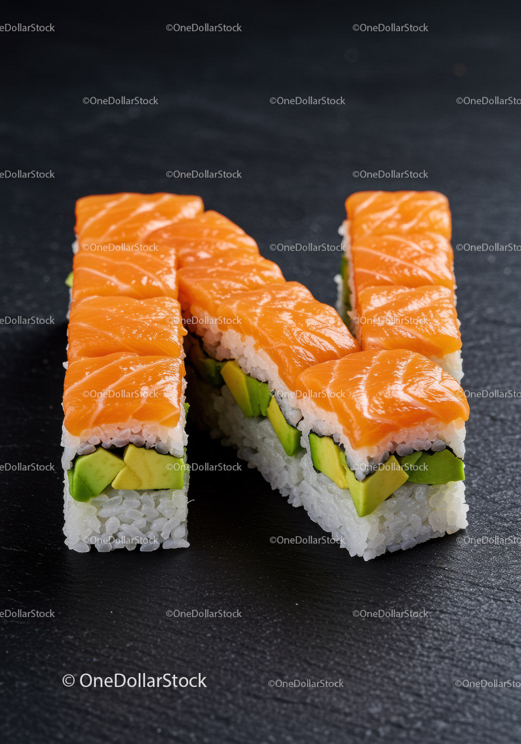 Świeże rolki sushi z łososiem i awokado na ciemnym talerzu łupkowym
