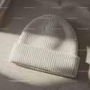 Cozy white knitted beanie hat on textured fabric