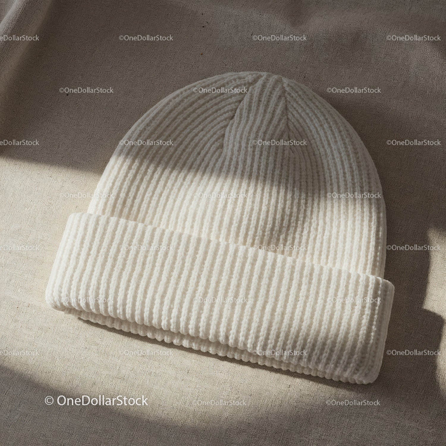 Cozy white knitted beanie hat on textured fabric