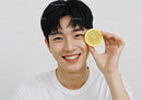 Young Man Holding Lemon Slice with Joyful Smile and Bright White Background