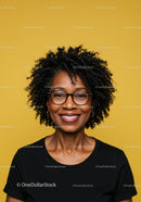 Confident Smiling Woman with Curly Hair and Glasses in Vibrant Setting