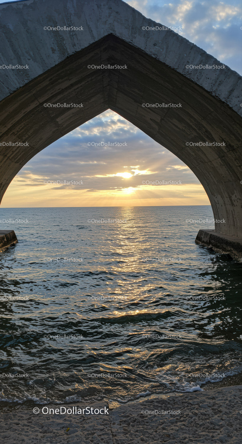 Architectural Concrete Arch Over Ocean at Sunset with Clouds