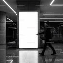 Blurred businessman walking by bright advertisement panel