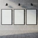 Three blank posters on concrete wall under industrial lights