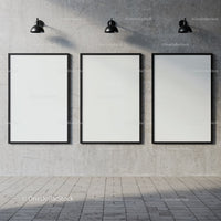 Three blank posters on concrete wall under industrial lights