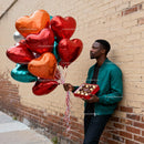 Man holding heart-shaped balloons and chocolate box