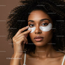 Close-up of a woman with curly hair applying eye patches