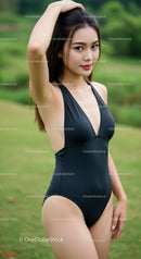 Elegant Woman in Black Swimsuit Posing Outdoors in Lush Green Setting