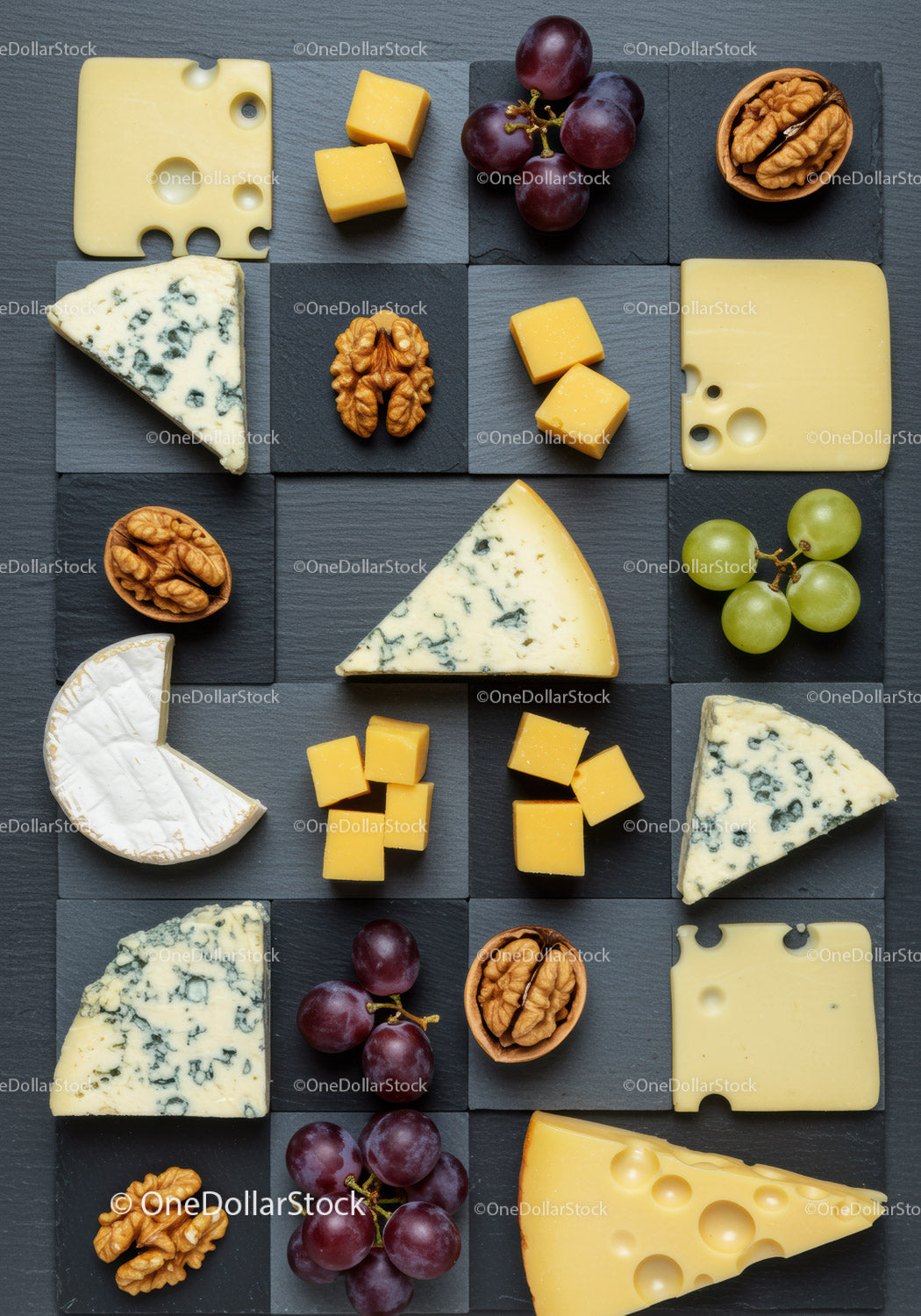 Variety of cheeses with grapes and walnuts on slate