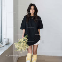 Fashionable Young Woman in Black T-Shirt and Yellow Socks Holding Flowers