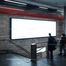 Commuters passing a large illuminated billboard in subway