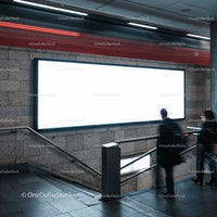 Commuters passing a large illuminated billboard in subway