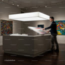 Man Reviewing Colorful Artwork in Modern Gallery Space