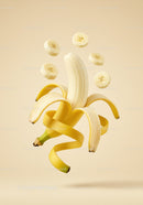 Floating peeled banana with sliced pieces against beige background