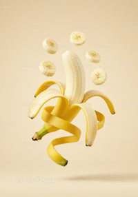 Floating peeled banana with sliced pieces against beige background