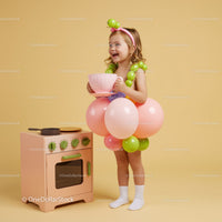 Happy little girl in balloon dress playing tea party
