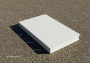 Closed white book resting on rough asphalt surface