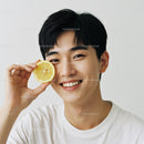Young Man Holding Lemon Half Smiling Cheerfully in Studio
