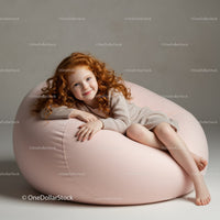 Smiling redhead girl relaxing on soft pink bean bag