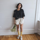 Casual Young Woman in Black T-Shirt and Beige Shorts Indoors