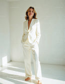 Elegant Woman in White Suit Posing Confidently in Minimalist Space