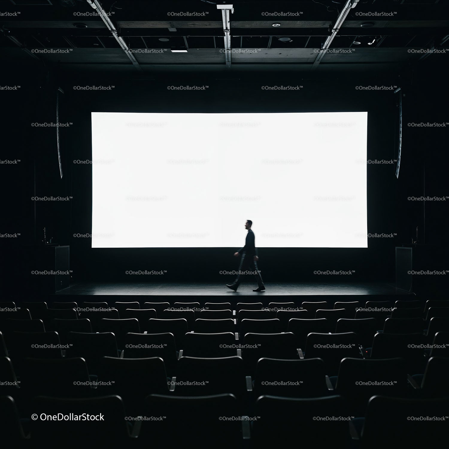 Man walking across empty dark movie theater stage