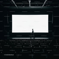 Man walking across empty dark movie theater stage