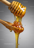 Golden honey dripping from wooden honey dipper into spoon