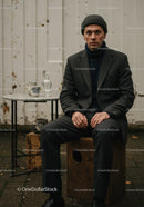 Man in autumn outfit sitting outside near rustic table