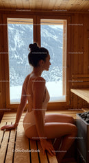 Young Woman Sitting in Sauna with Snow-Covered Mountain View