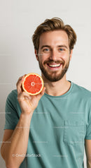 Smiling Young Man Holding Grapefruit Slice in Bright Casual Setting