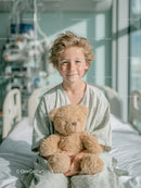 Joyful Young Child Holding Teddy Bear in Bright Hospital Room